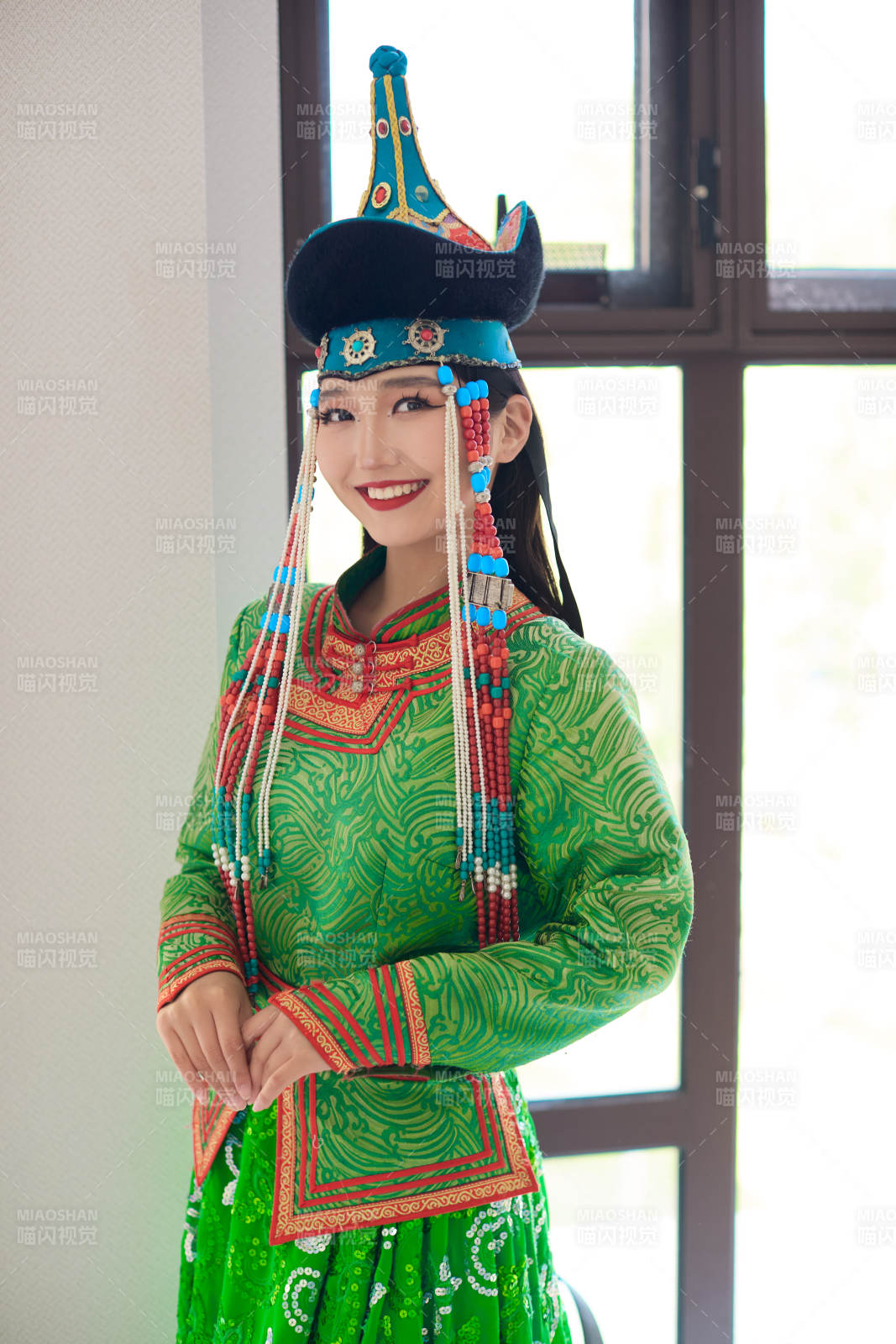 室內穿著綠色蒙古袍的蒙古族年輕女性