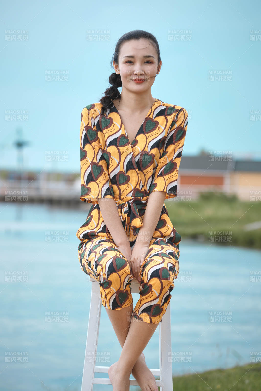 悠閑的坐在美麗湖岸碼頭的亞洲年輕女性人像