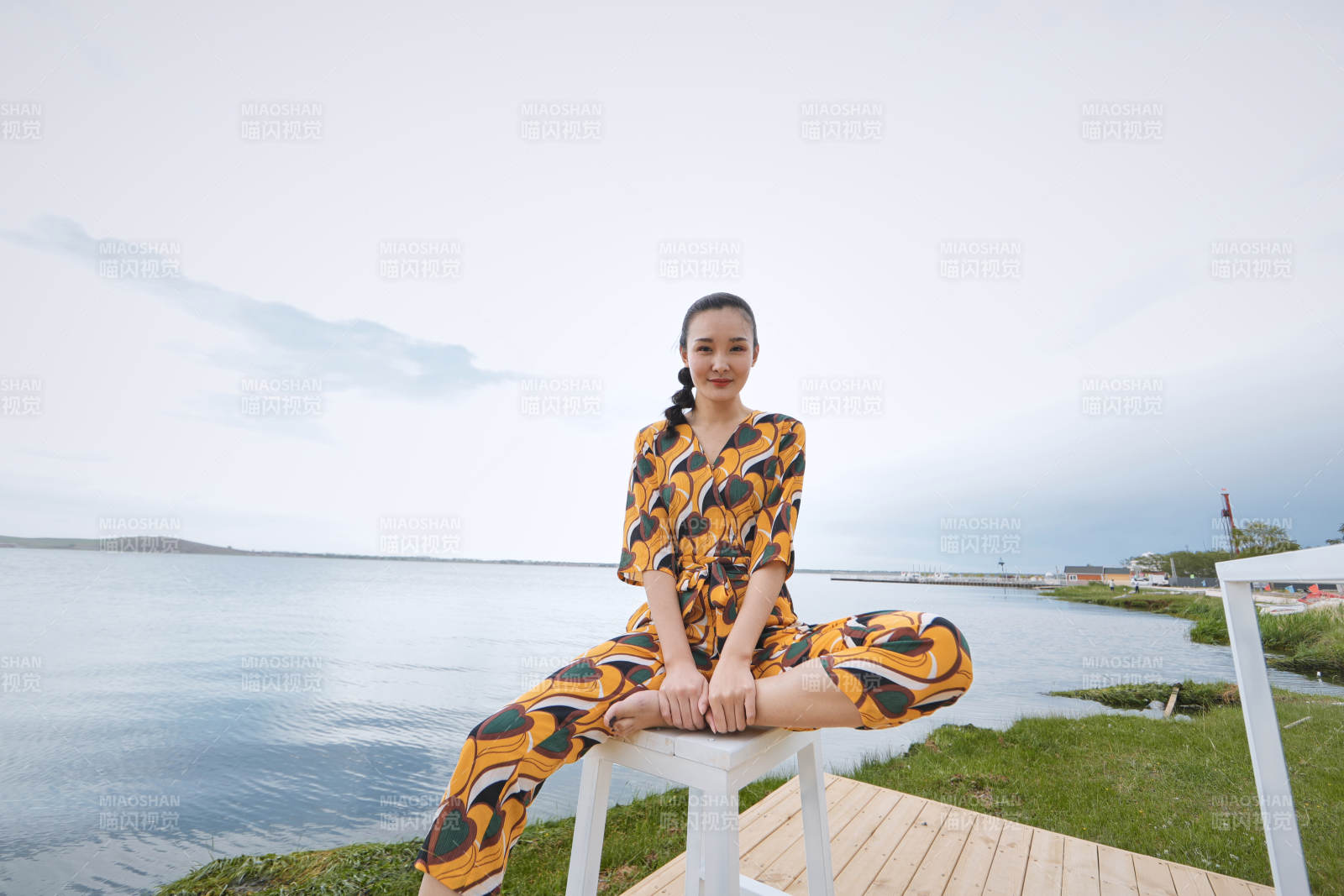 悠閑的坐在美麗湖岸碼頭的亞洲年輕女性人像