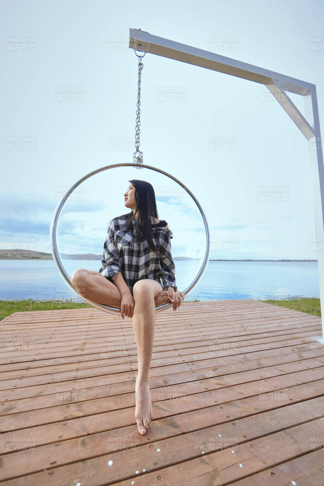 草原湖畔坐在透明秋千里的亞洲年輕女性人像