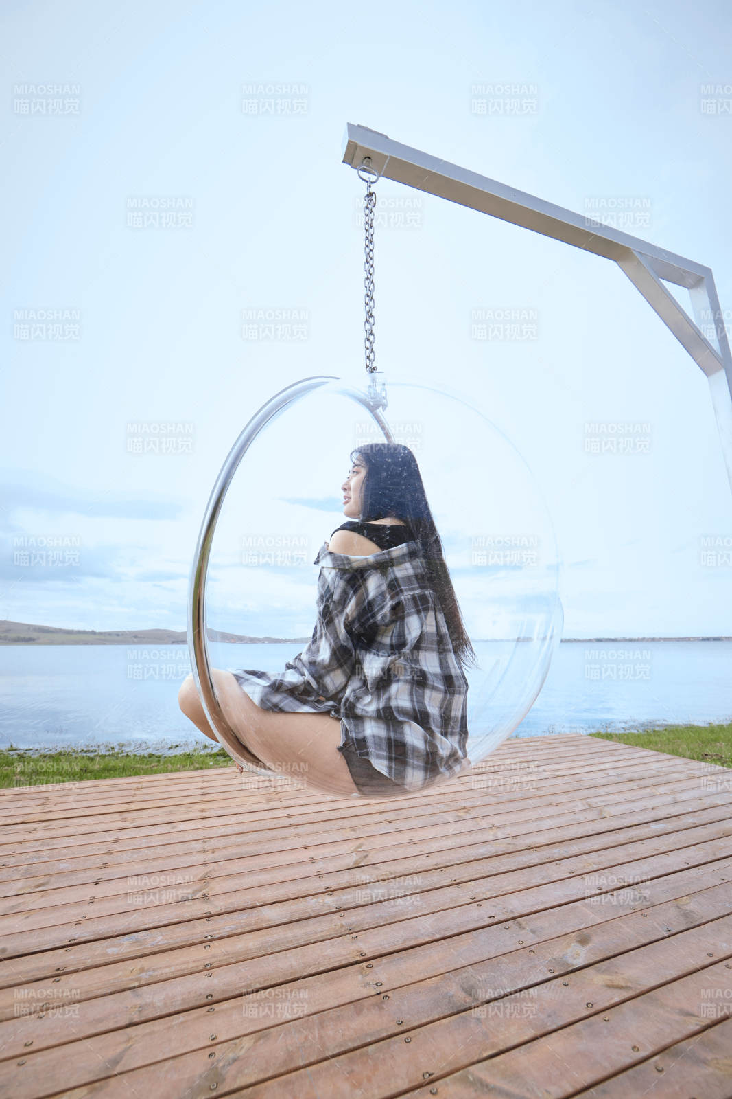 草原湖畔坐在透明秋千里的亞洲年輕女性人像