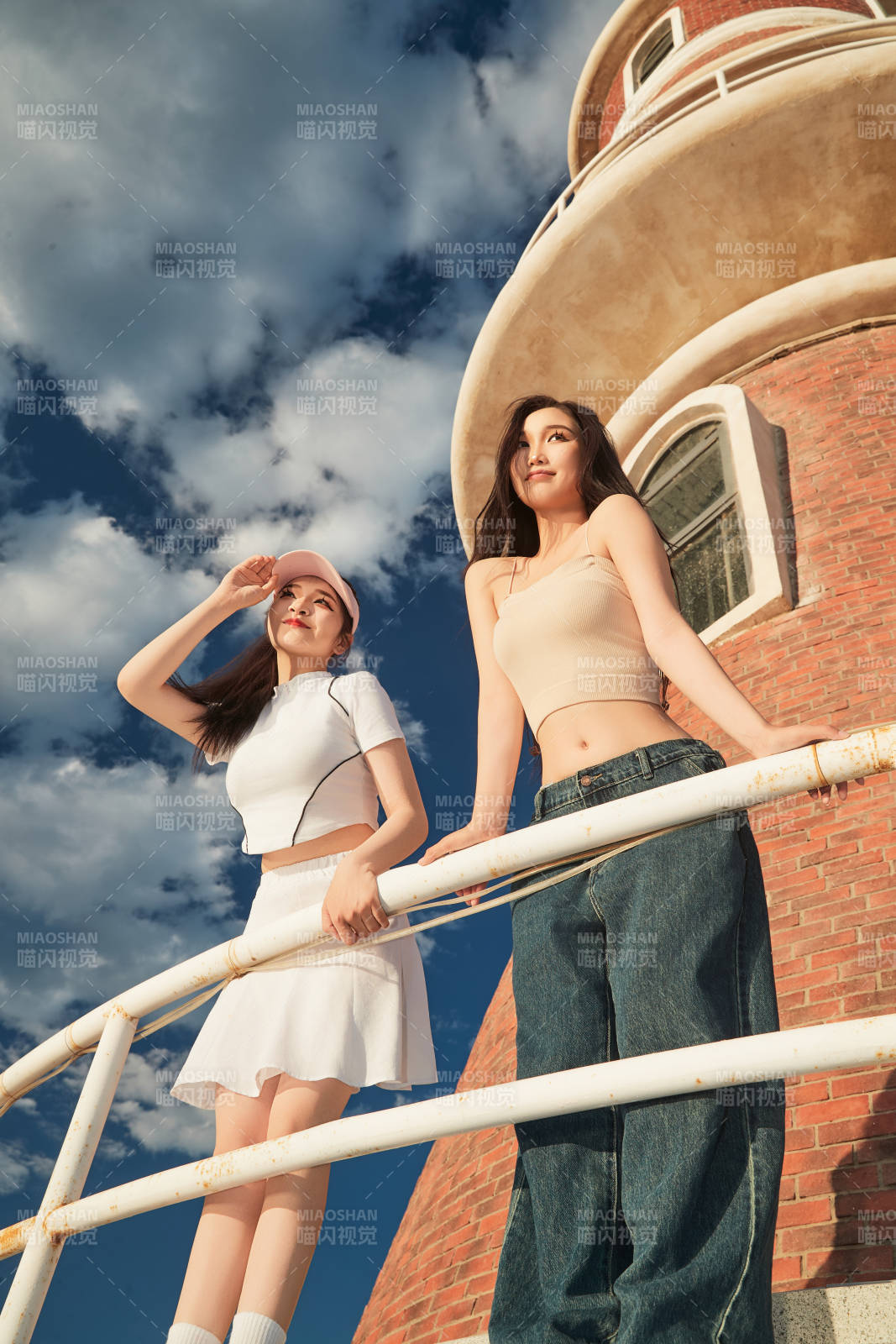 盛夏在景區湖邊燈塔上拍照游玩的美女們