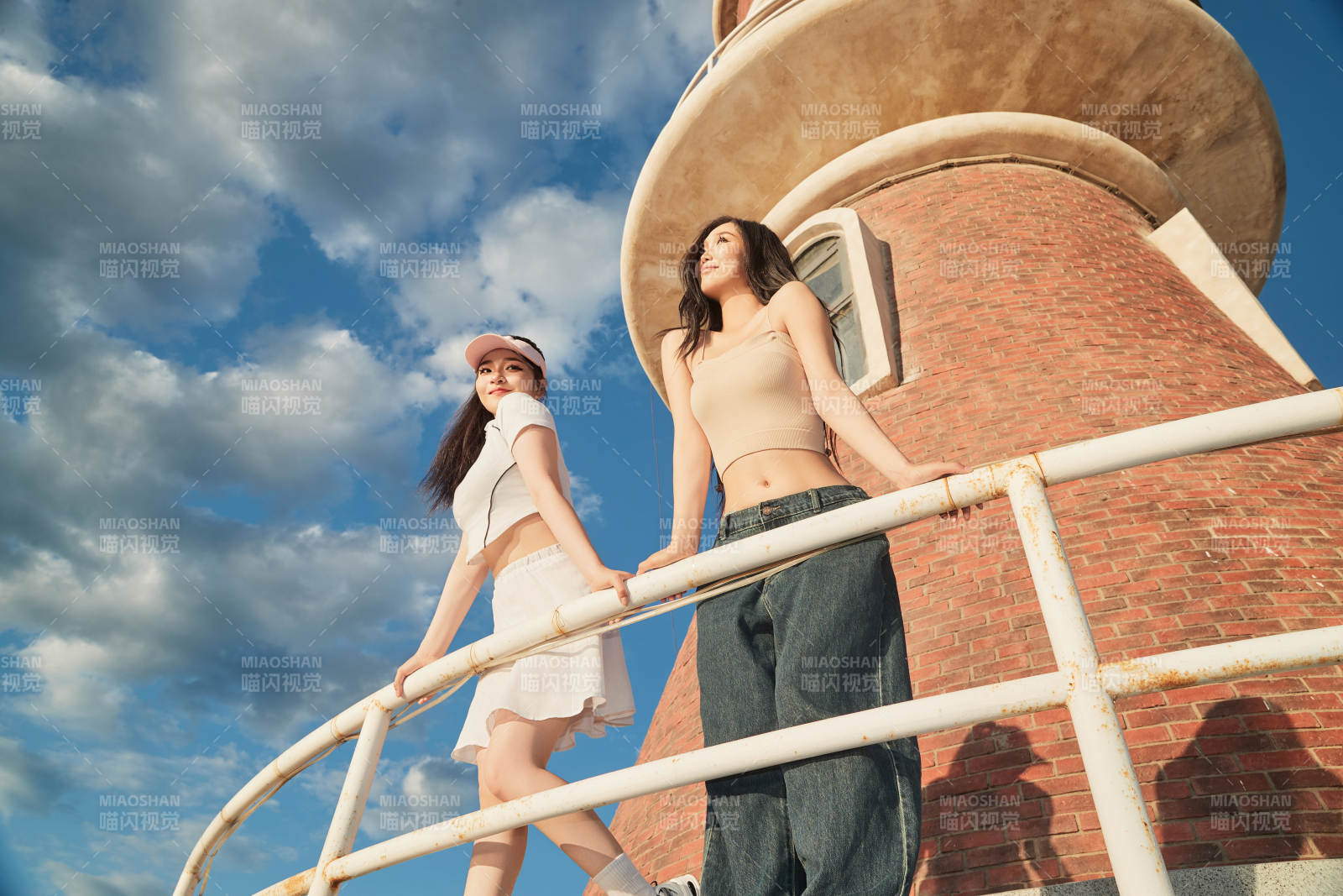 盛夏在景區(qū)湖邊燈塔上拍照游玩的美女們