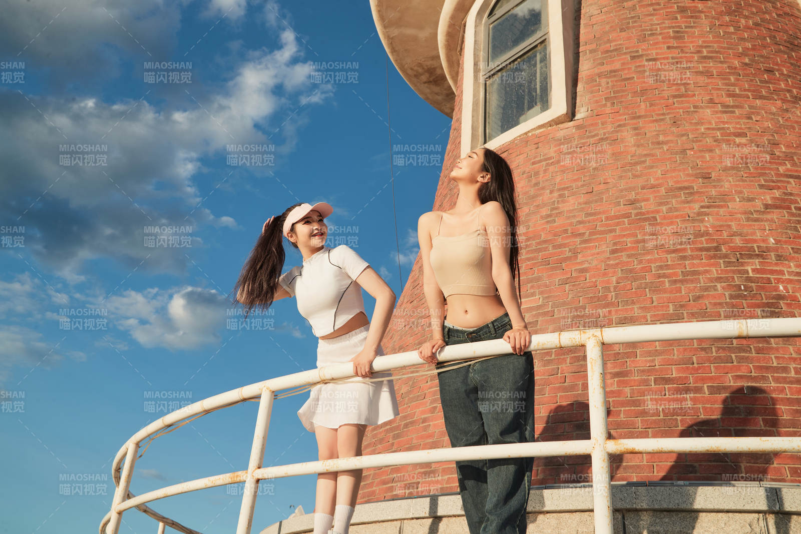 盛夏在景区湖边灯塔上拍照游玩的美女们