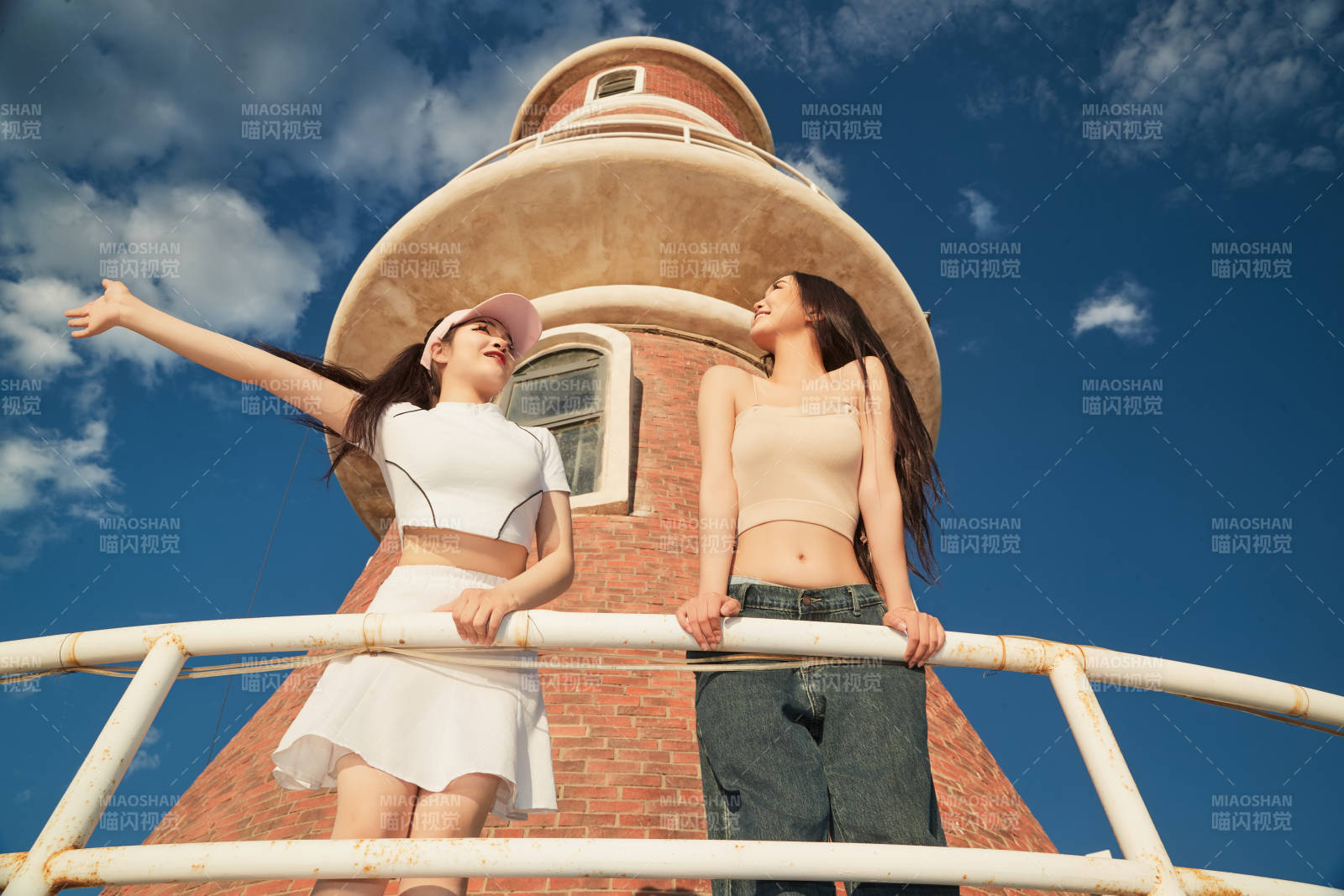 盛夏在景區湖邊燈塔上拍照游玩的美女們