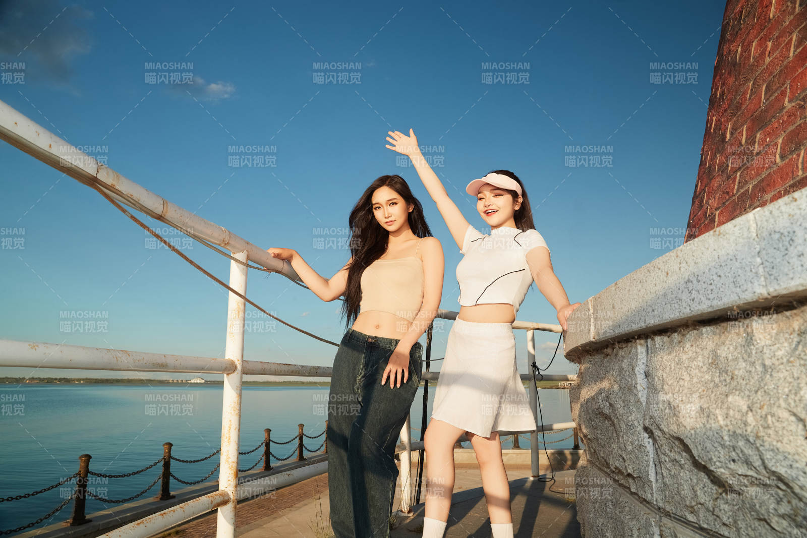 盛夏在景區湖邊燈塔上拍照游玩的美女們