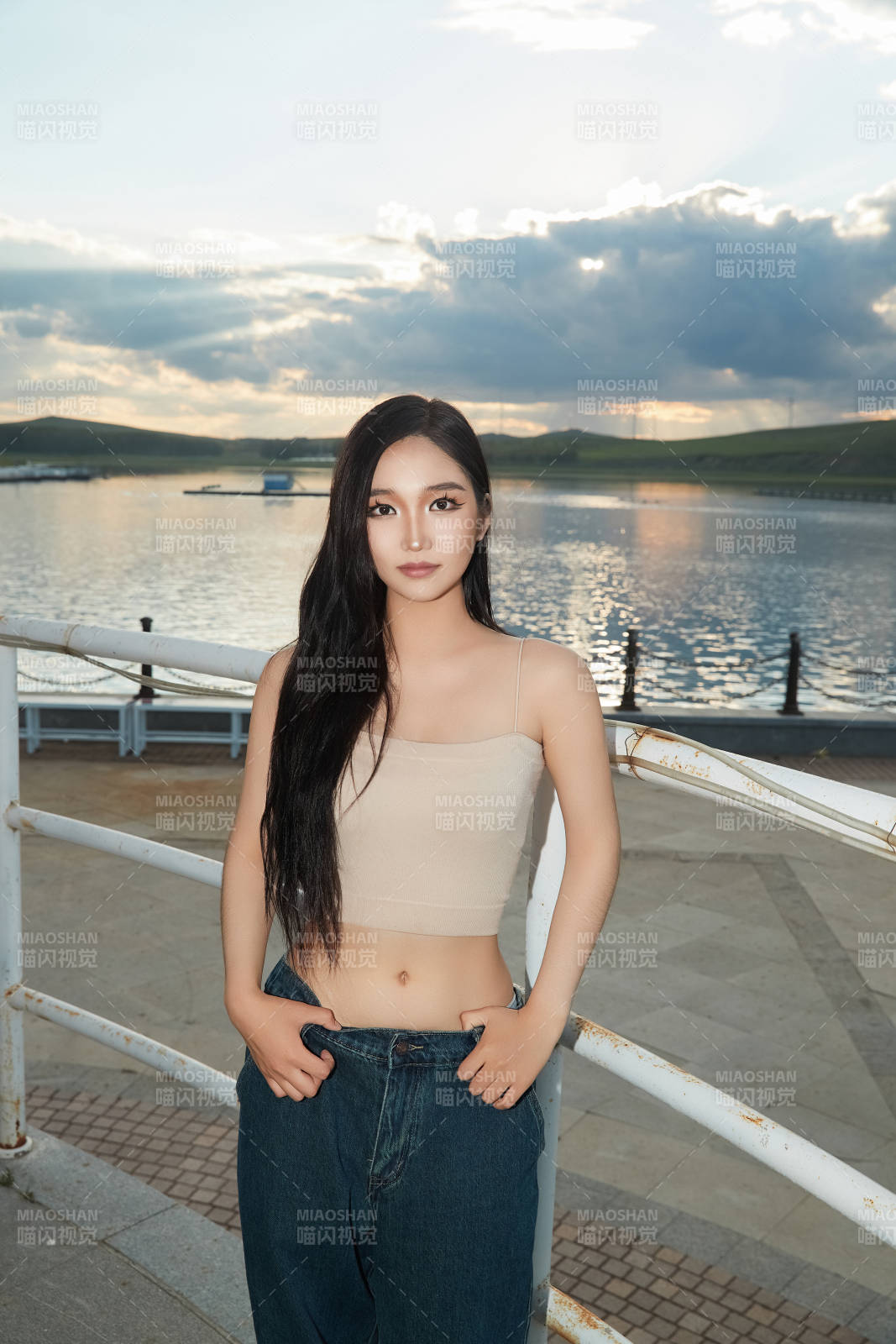 盛夏在景區(qū)湖邊燈塔上拍照游玩的美女