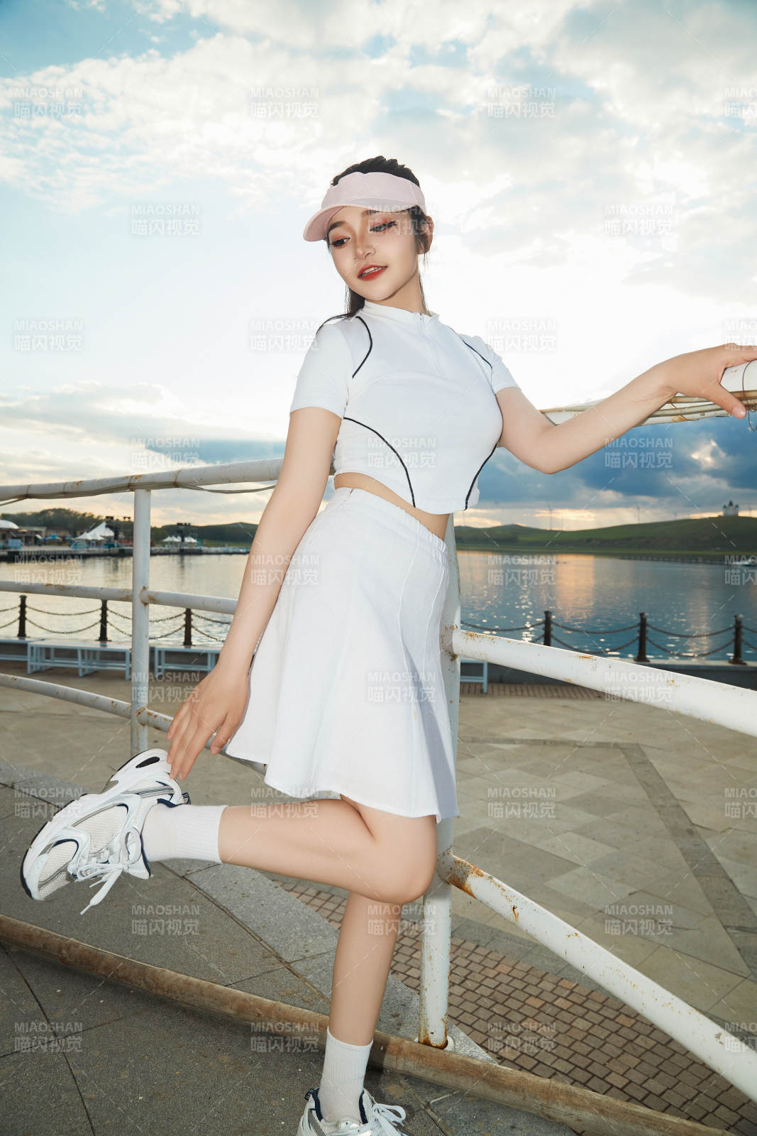 盛夏在景區(qū)湖邊燈塔上拍照游玩的美女