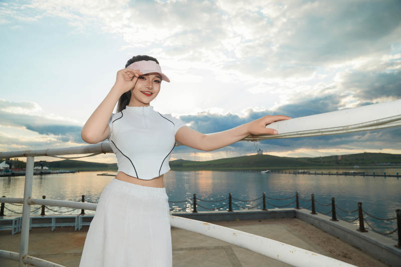 盛夏在景区湖边灯塔上拍照游玩的美女