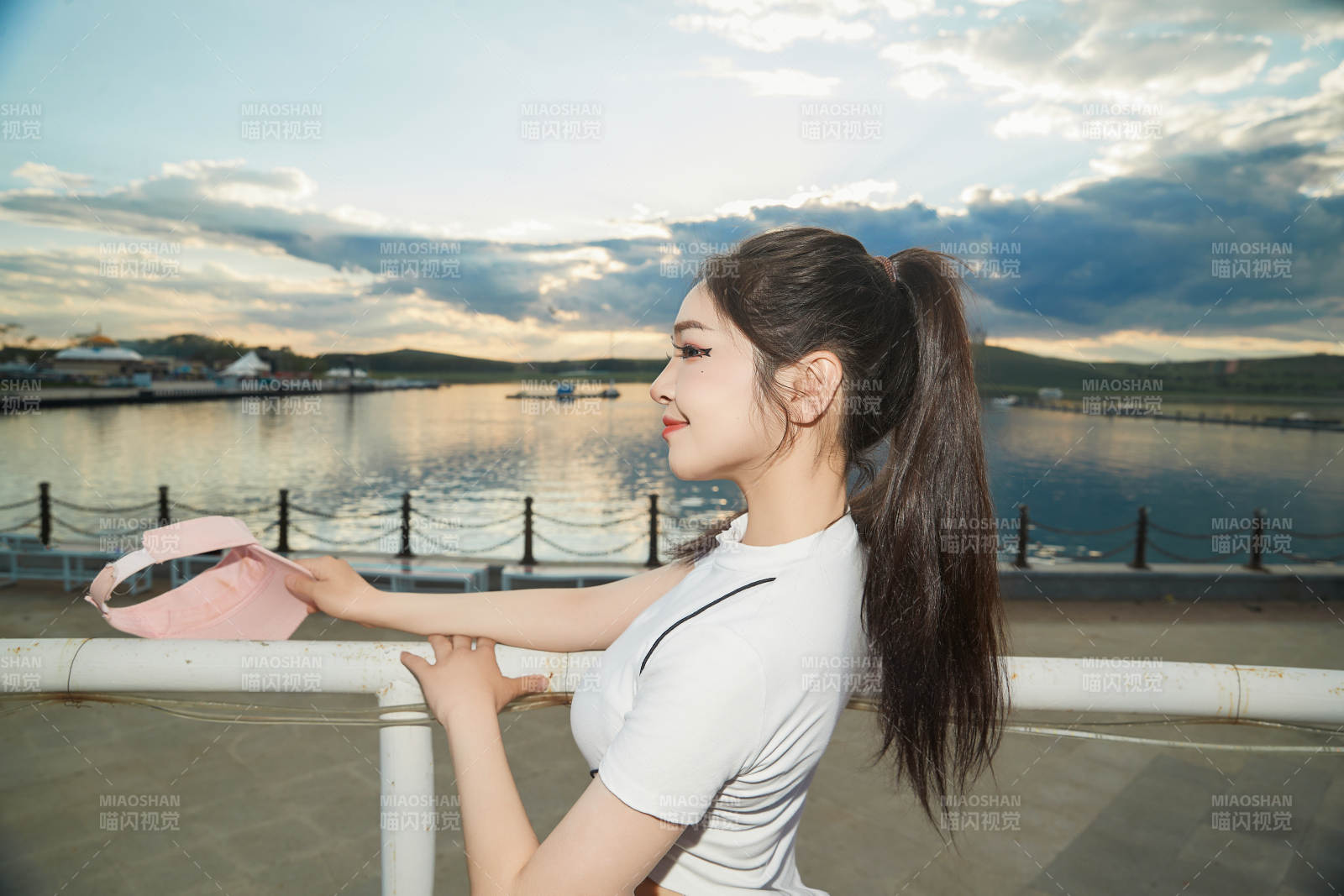 盛夏在景區湖邊燈塔上拍照游玩的美女