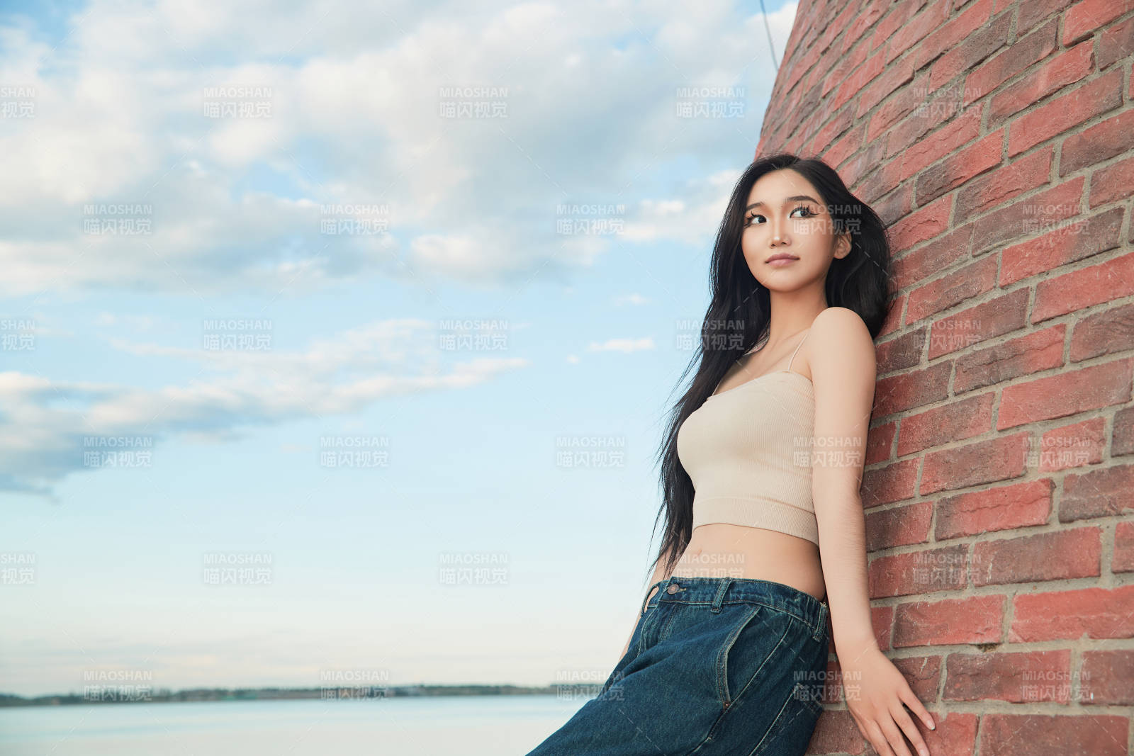 盛夏在景區湖邊燈塔上拍照游玩的美女