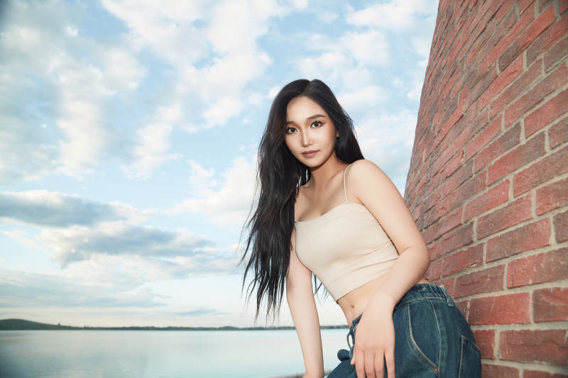 盛夏在景区湖边灯塔上拍照游玩的美女