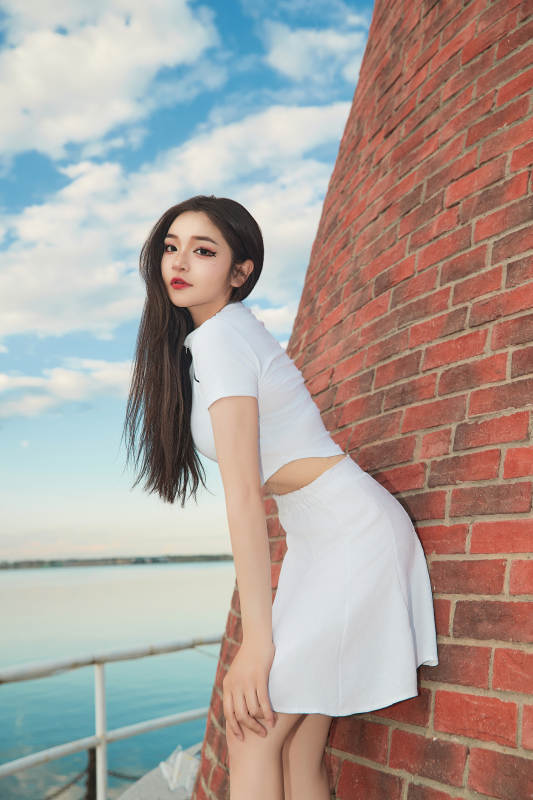 盛夏在景区湖边灯塔上拍照游玩的美女