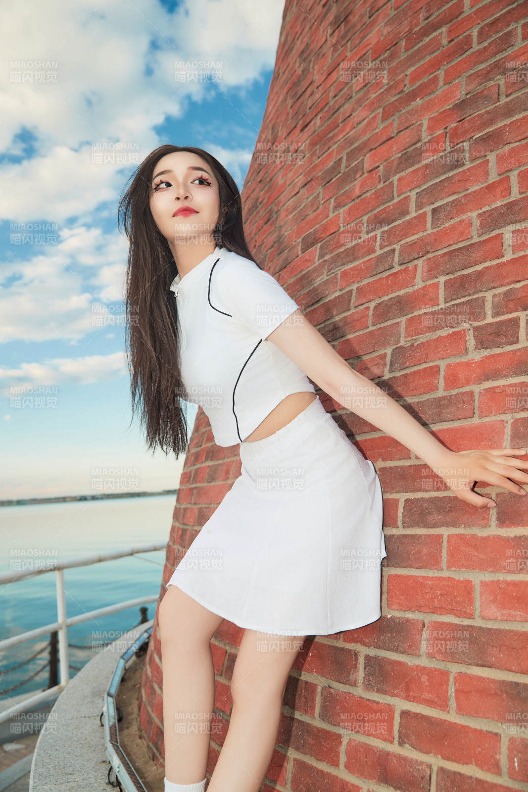 盛夏在景區湖邊燈塔上拍照游玩的美女