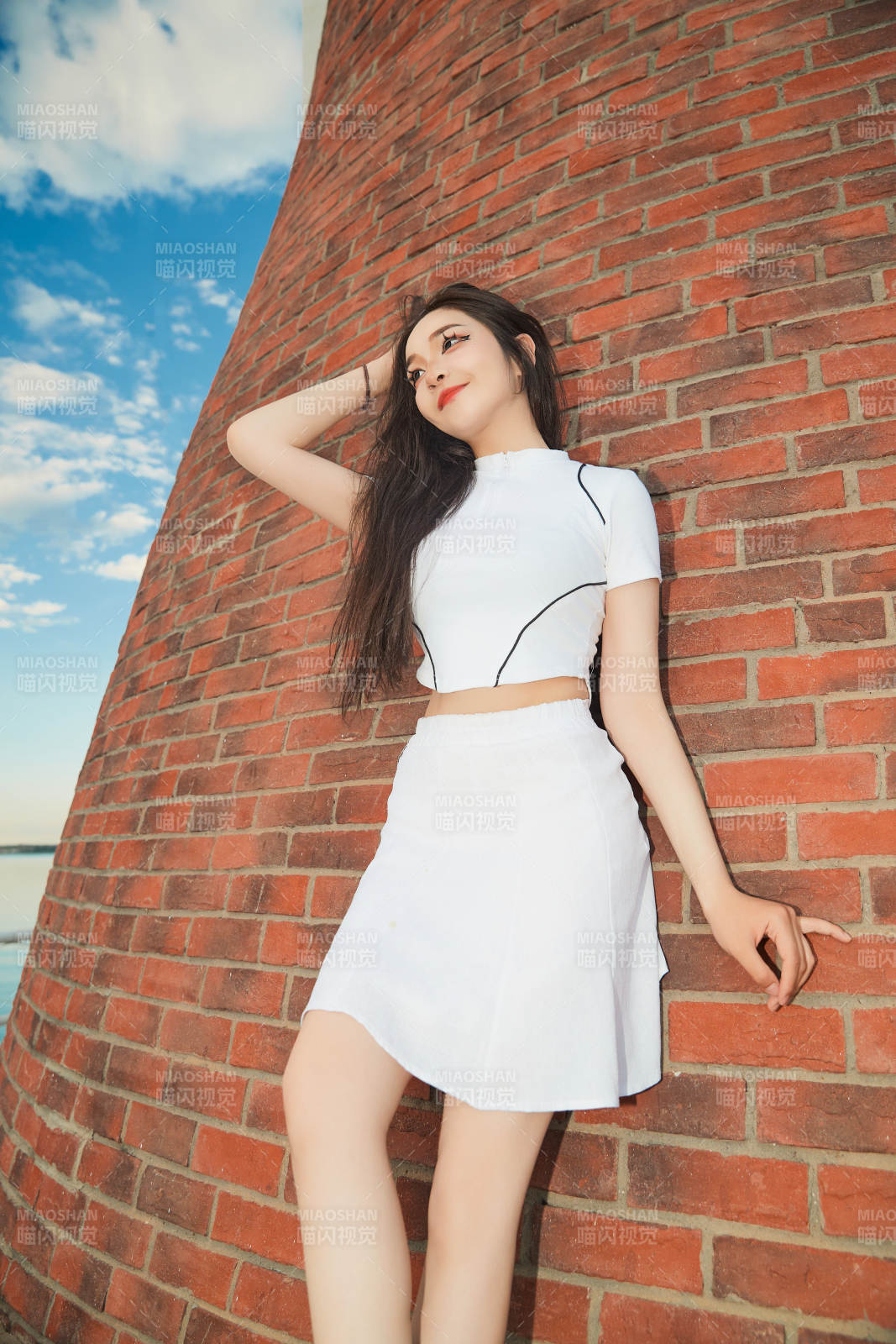 盛夏在景區(qū)湖邊燈塔上拍照游玩的美女