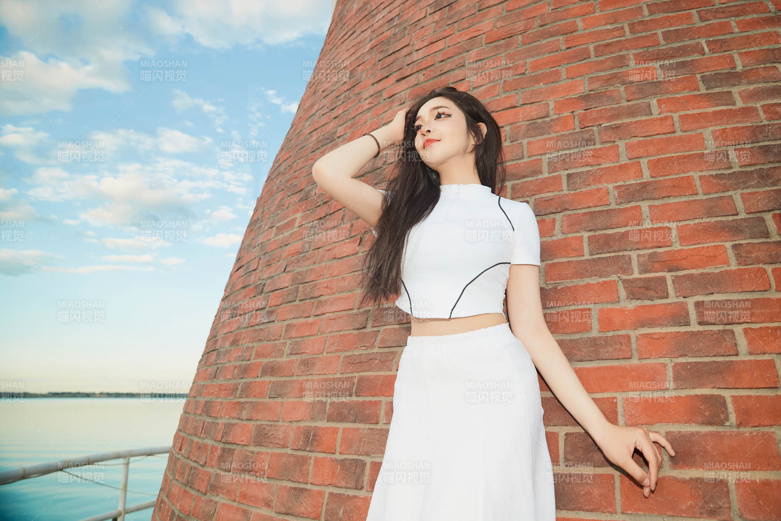 盛夏在景區湖邊燈塔上拍照游玩的美女