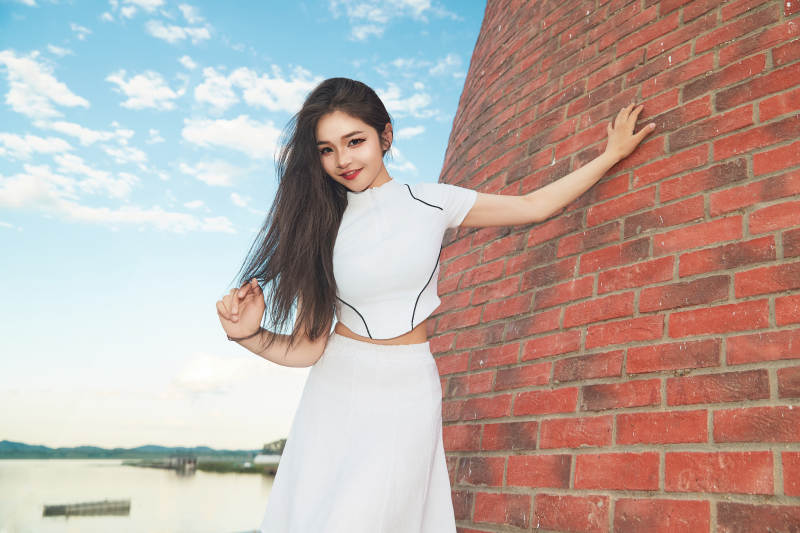 盛夏在景区湖边灯塔上拍照游玩的美女