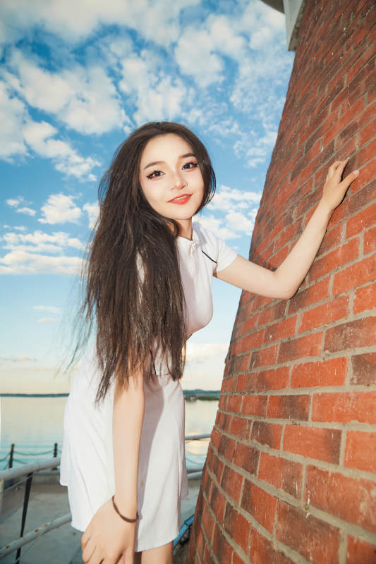 盛夏在景区湖边灯塔上拍照游玩的美女