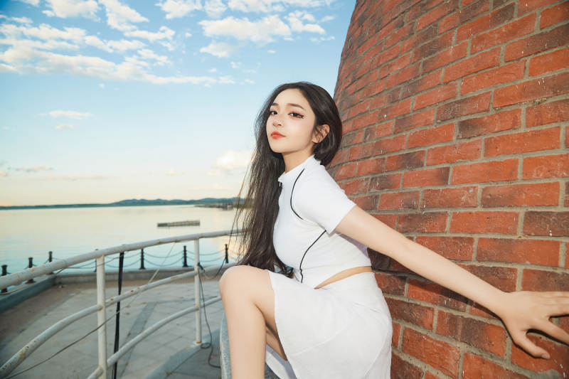 盛夏在景区湖边灯塔上拍照游玩的美女