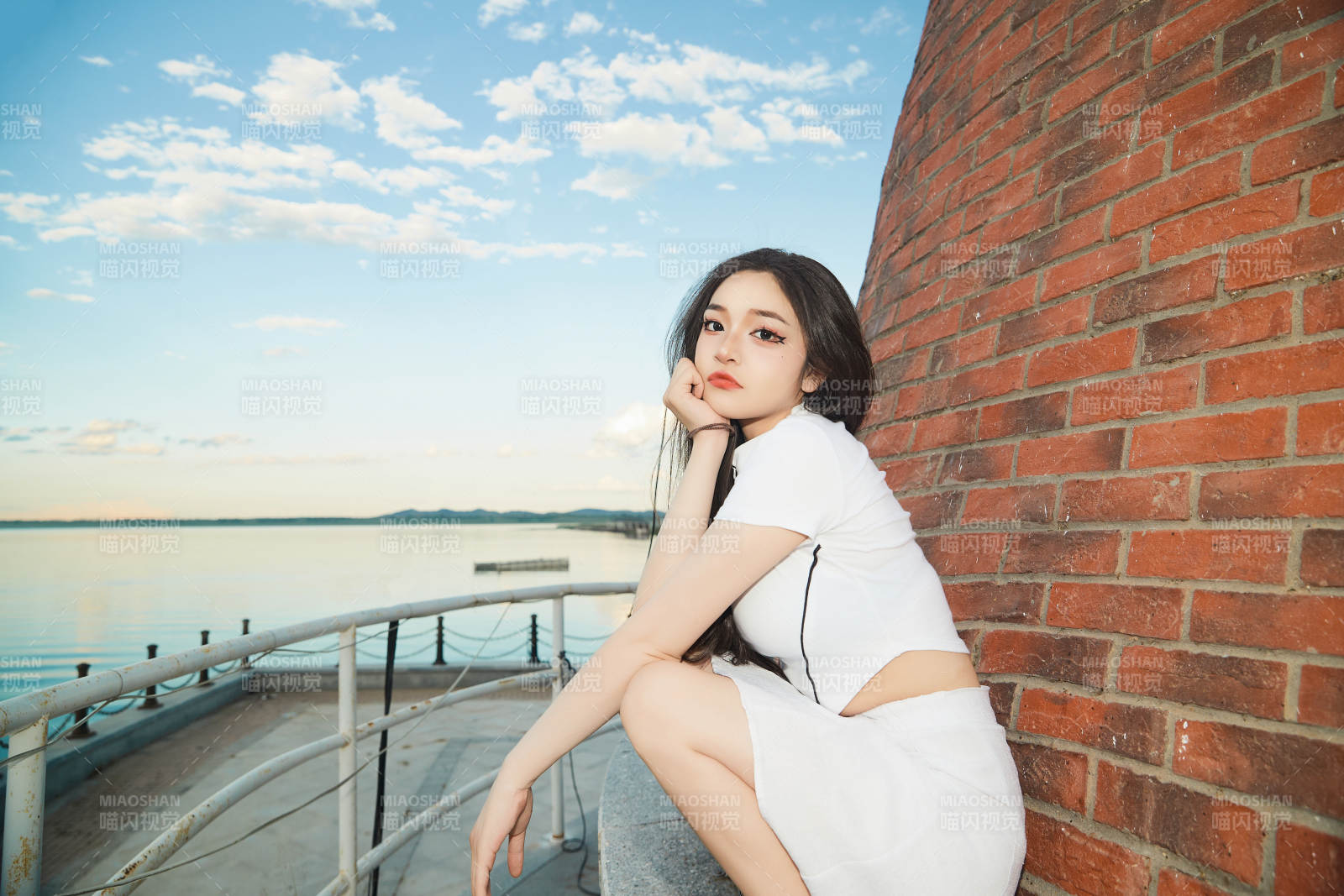 盛夏在景區湖邊燈塔上拍照游玩的美女