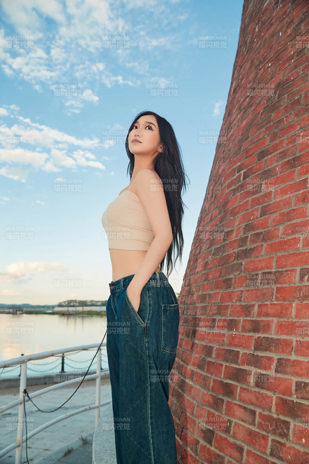 盛夏在景區湖邊燈塔上拍照游玩的美女