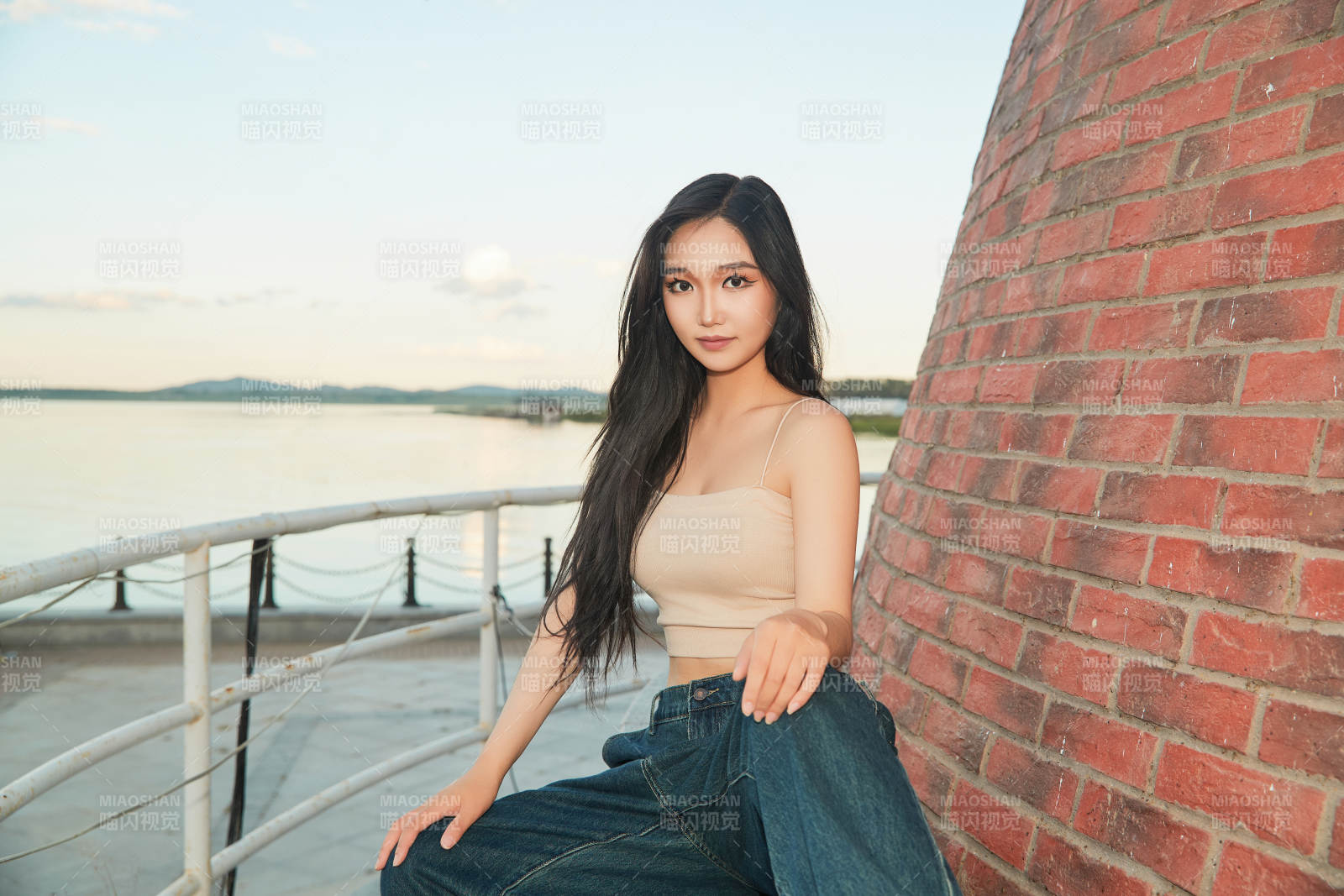 盛夏在景区湖边灯塔上拍照游玩的美女