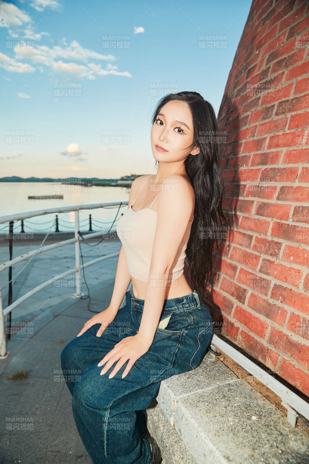 盛夏在景區湖邊燈塔上拍照游玩的美女