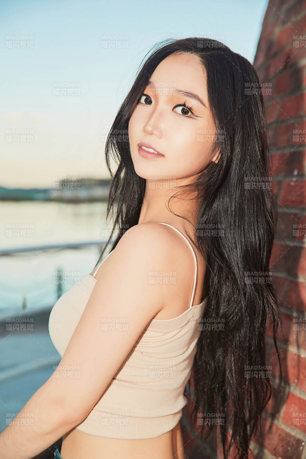 盛夏在景区湖边灯塔上拍照游玩的美女图片