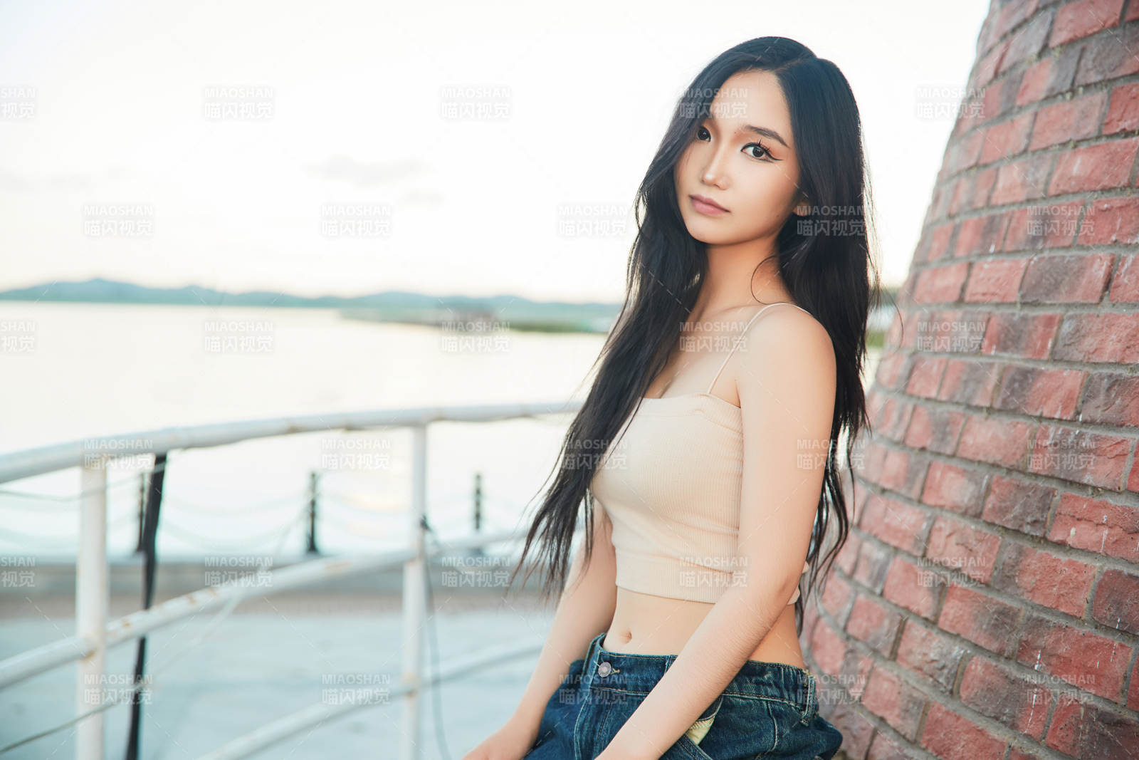 盛夏在景区湖边灯塔上拍照游玩的美女图片