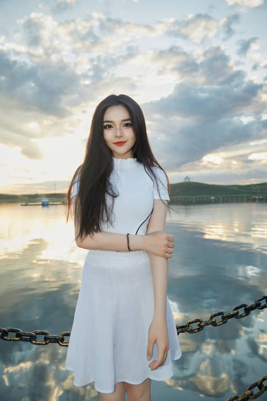 傍晚在湖边欣赏风景拍照的亚洲美女