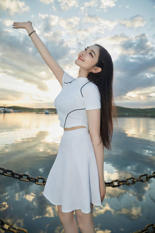 傍晚在湖边欣赏风景拍照的亚洲美女