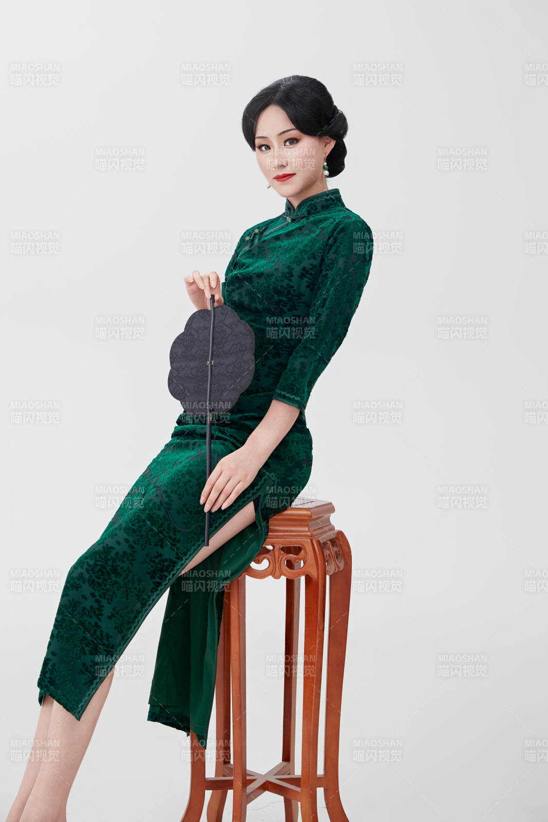 手拿紙扇身著中式旗袍坐在凳子上的美女