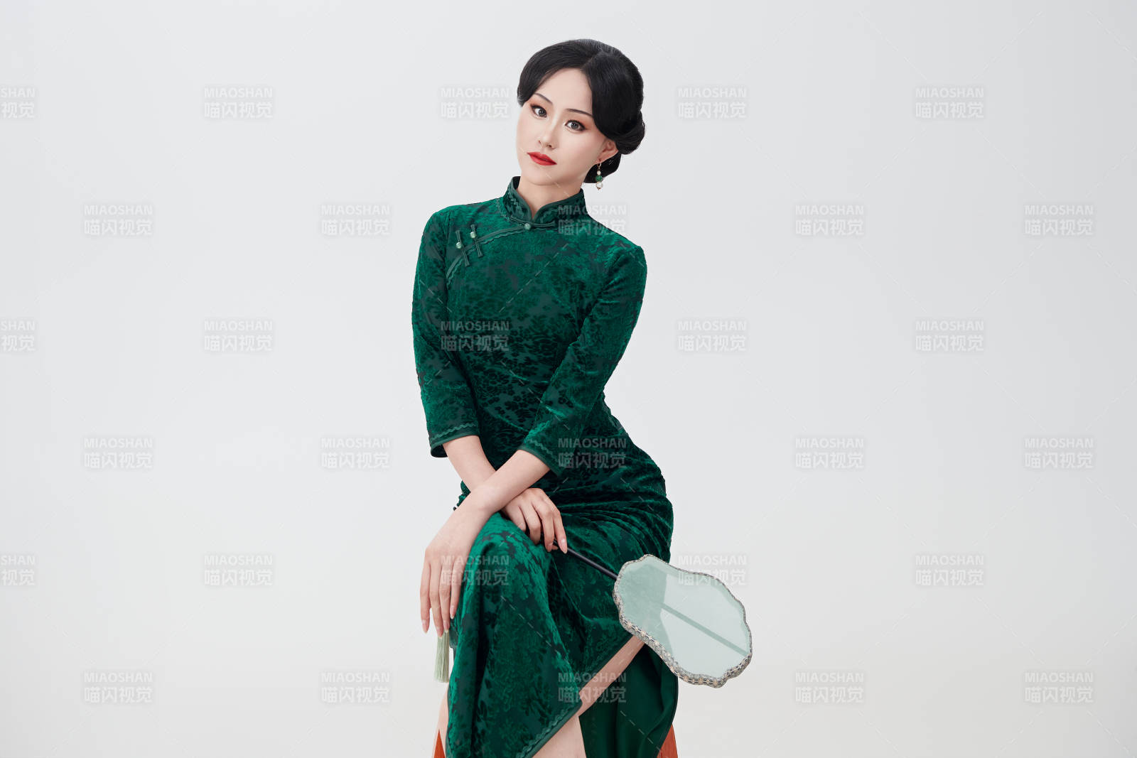 手拿紙扇身著中式旗袍坐在凳子上的美女