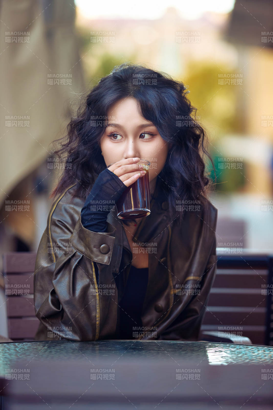 身穿复古皮衣在户外喝咖啡的东方美女