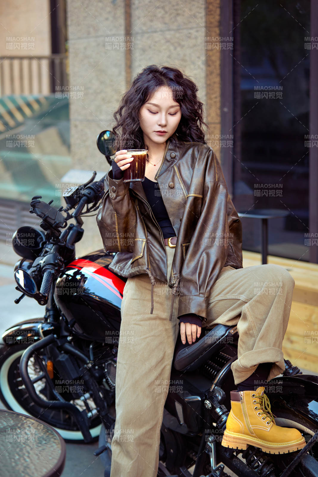 手拿冰美式咖啡坐在摩托上的亞洲美女