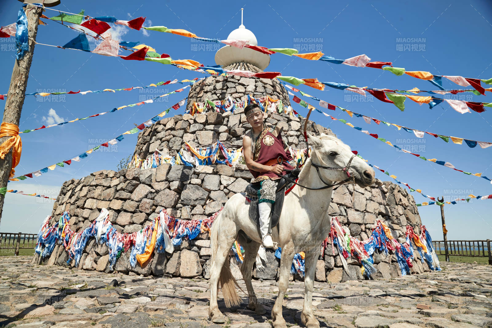 草原敖包前騎馬拉弓射箭的蒙古弓箭手