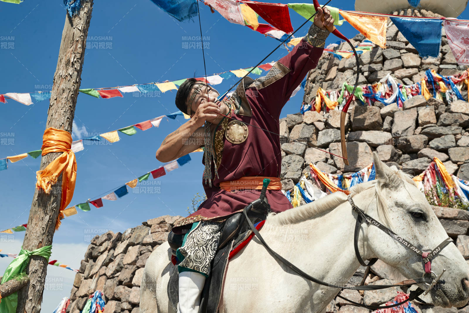 草原敖包前骑马拉弓射箭的蒙古弓箭手