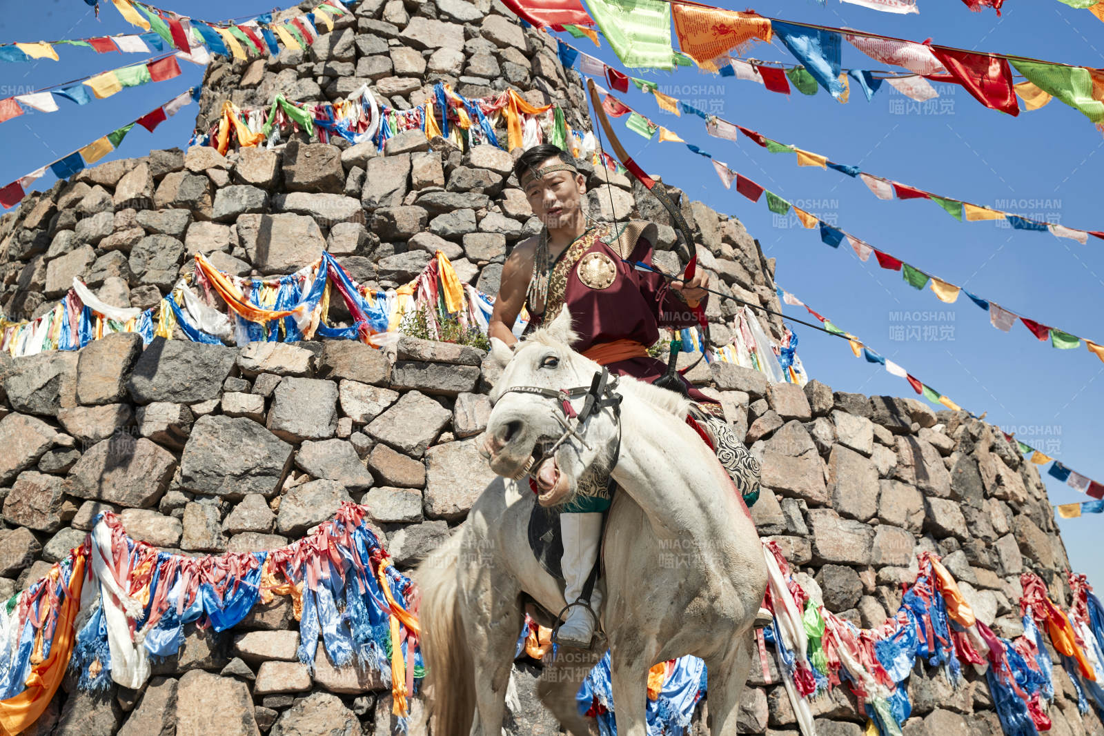草原敖包前騎馬拉弓射箭的蒙古弓箭手