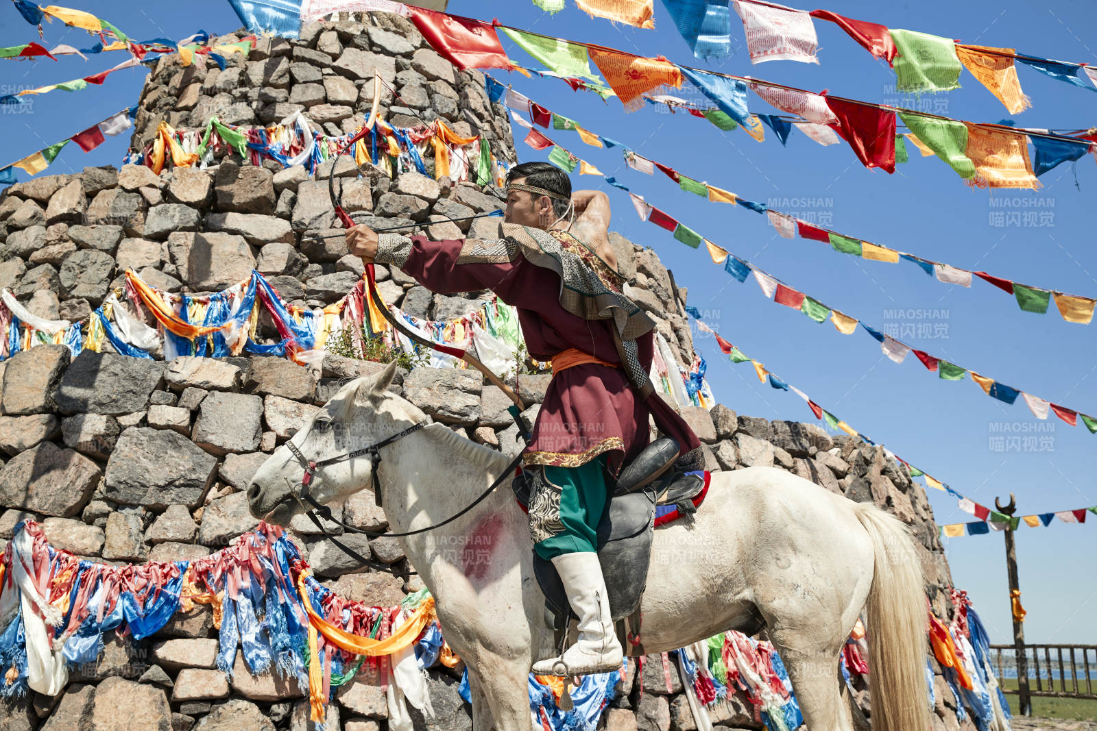 草原敖包前騎馬拉弓射箭的蒙古弓箭手