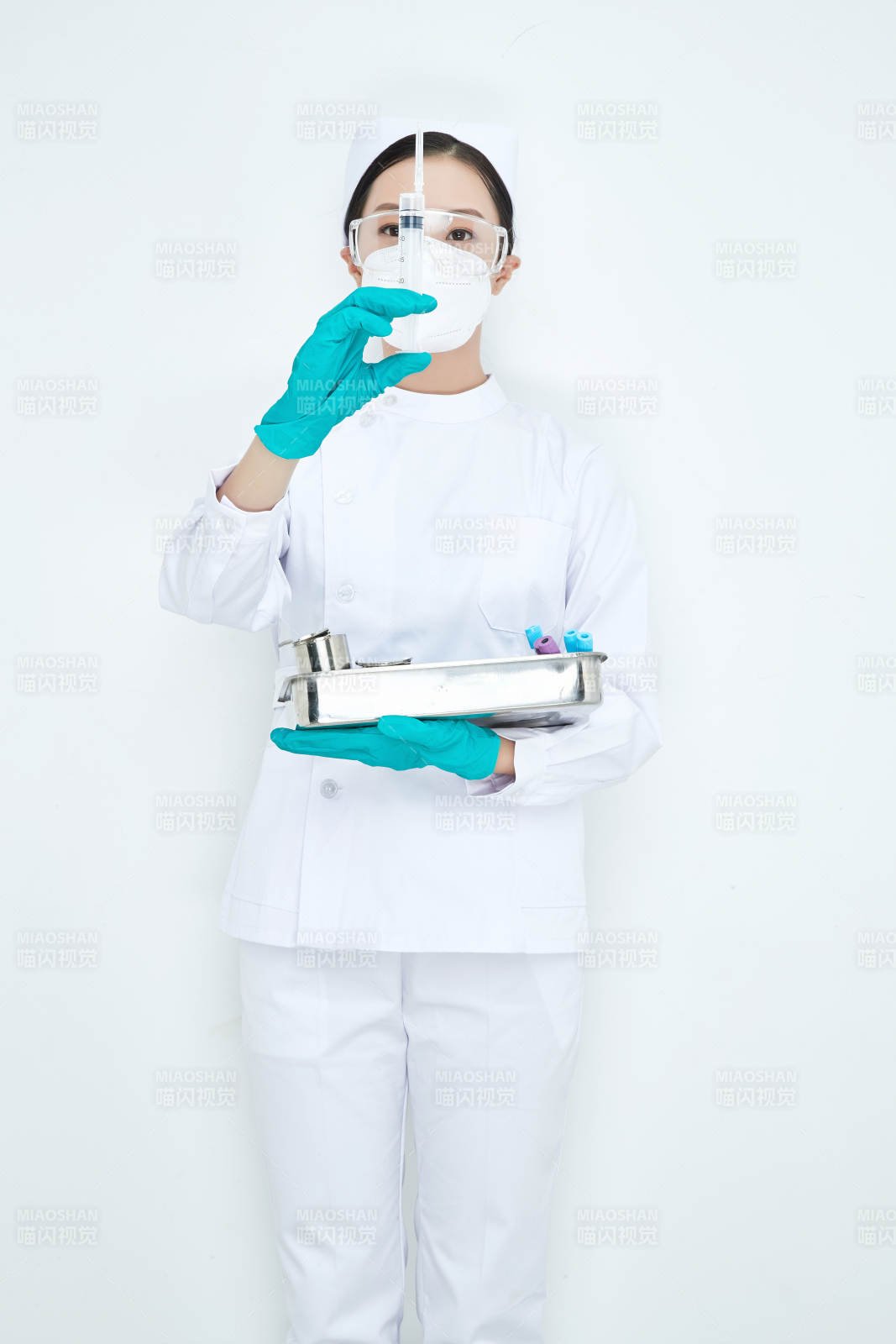 身穿护士服手抱化验托盘的年轻女护士图片