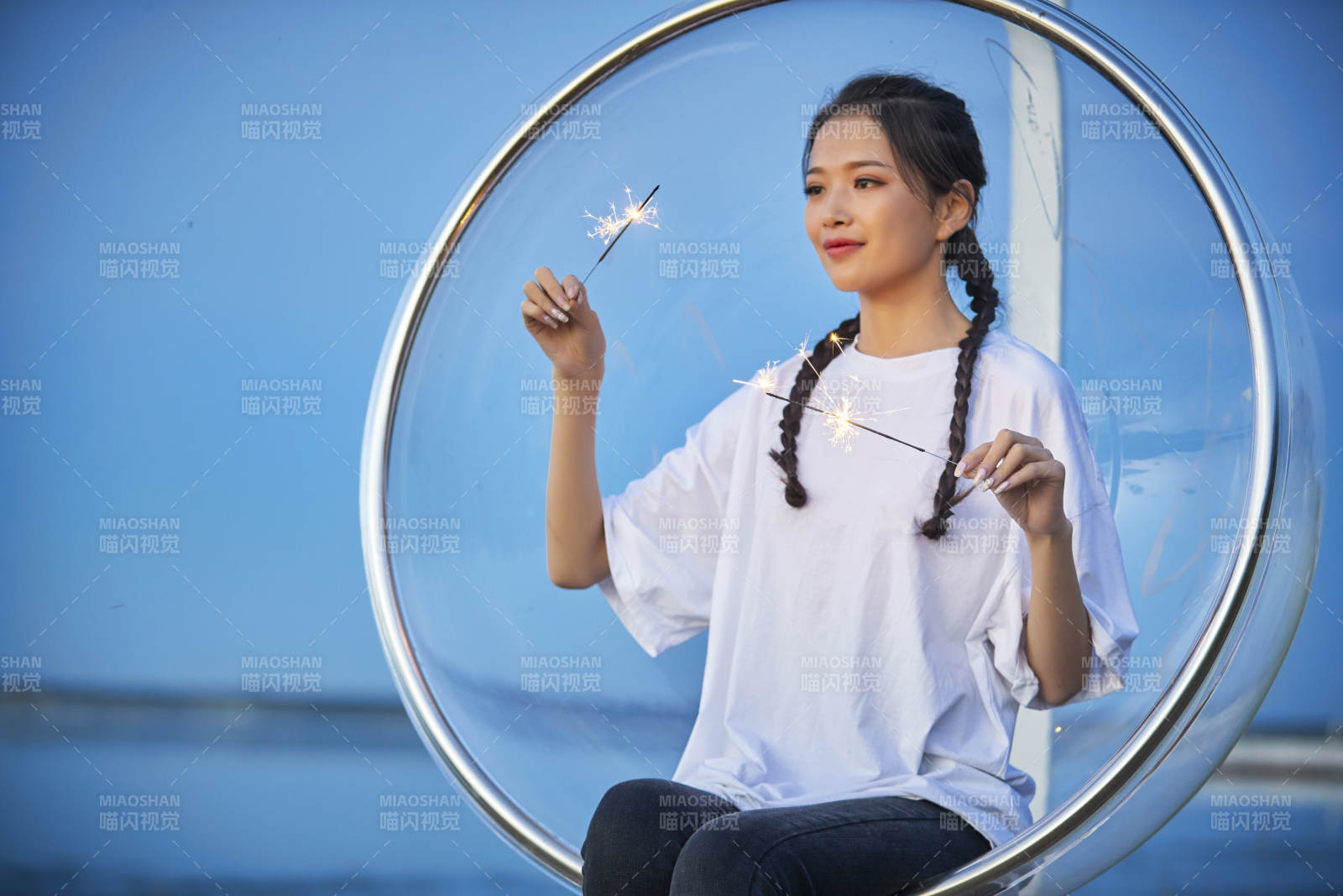 傍晚湖畔透明秋千上燃放仙女棒的可愛少女