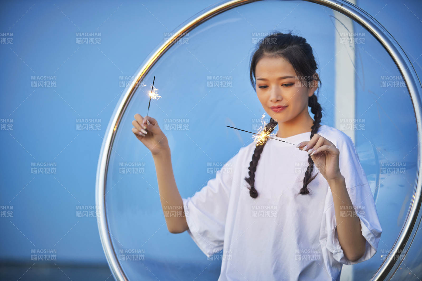 傍晚湖畔透明秋千上燃放仙女棒的可愛少女