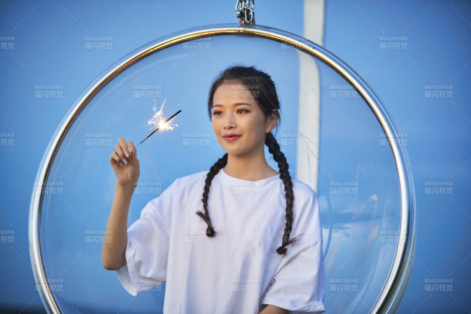 傍晚湖畔透明秋千上燃放仙女棒的可愛少女