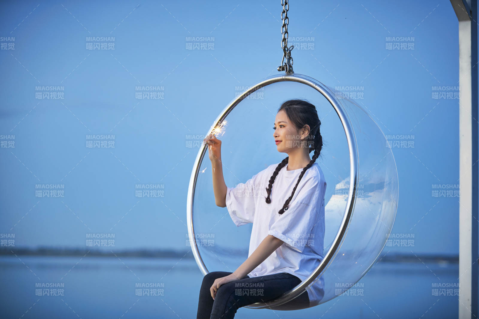 傍晚湖畔透明秋千上燃放仙女棒的可愛少女