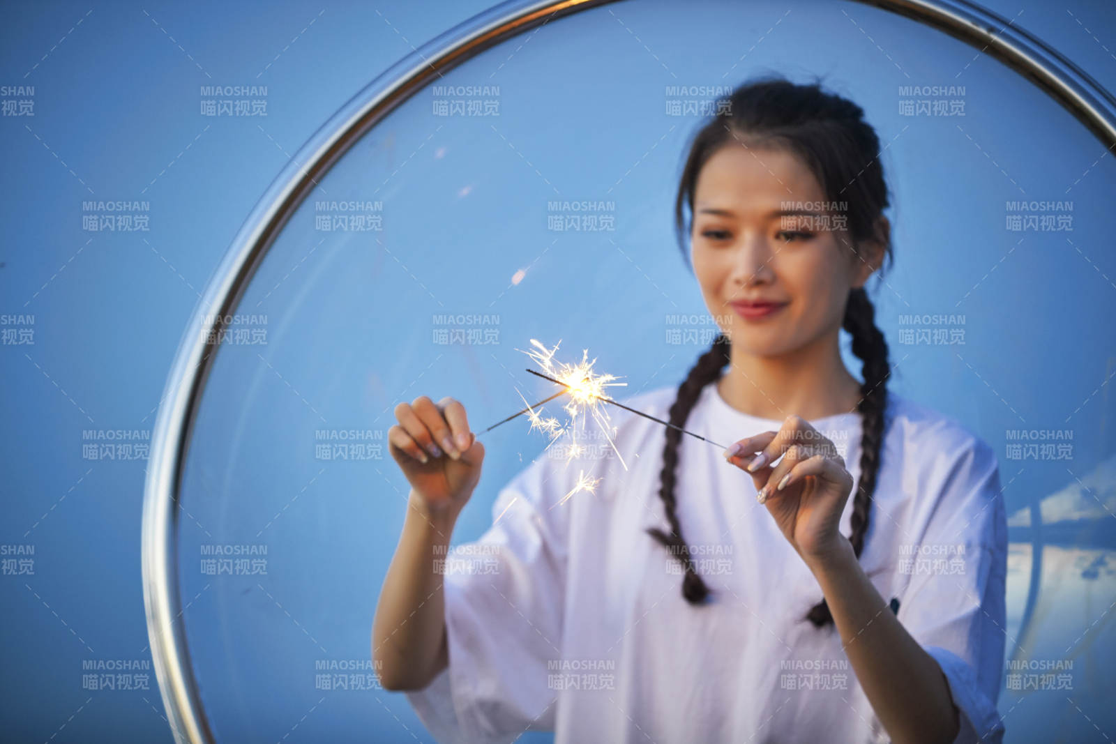 傍晚湖畔透明秋千上燃放仙女棒的可爱少女