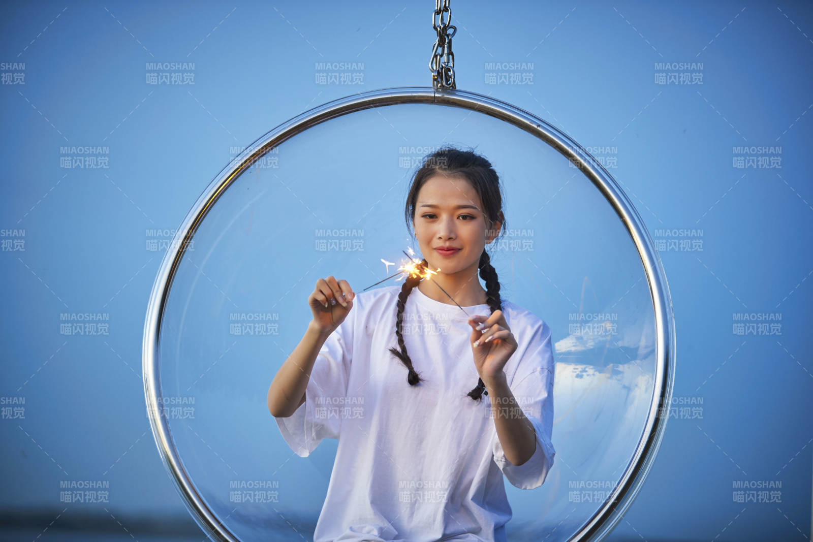 傍晚湖畔透明秋千上燃放仙女棒的可愛少女