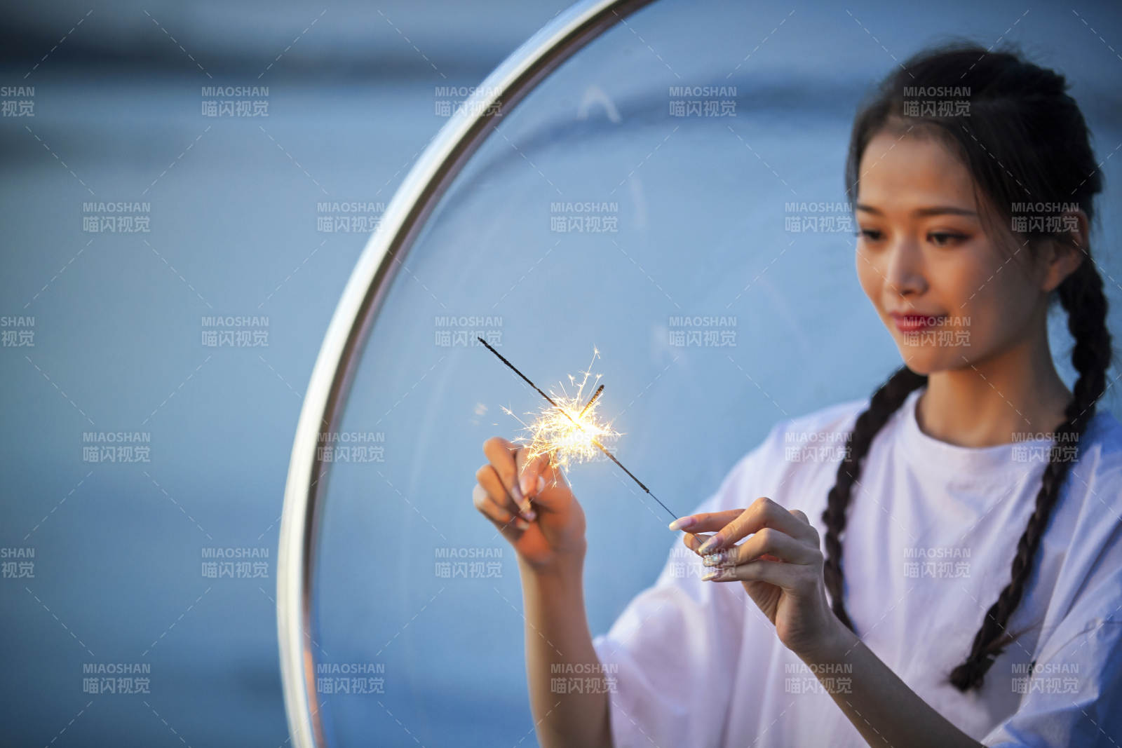 傍晚湖畔透明秋千上燃放仙女棒的可爱少女