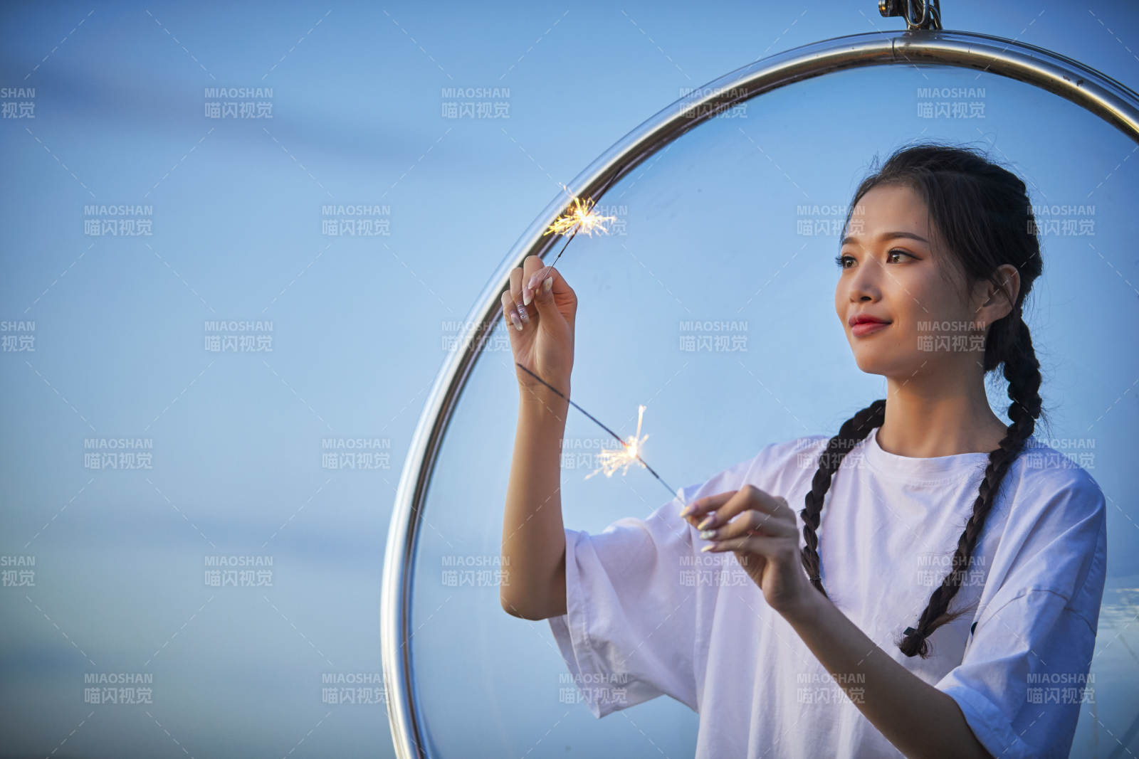 傍晚湖畔透明秋千上燃放仙女棒的可爱少女