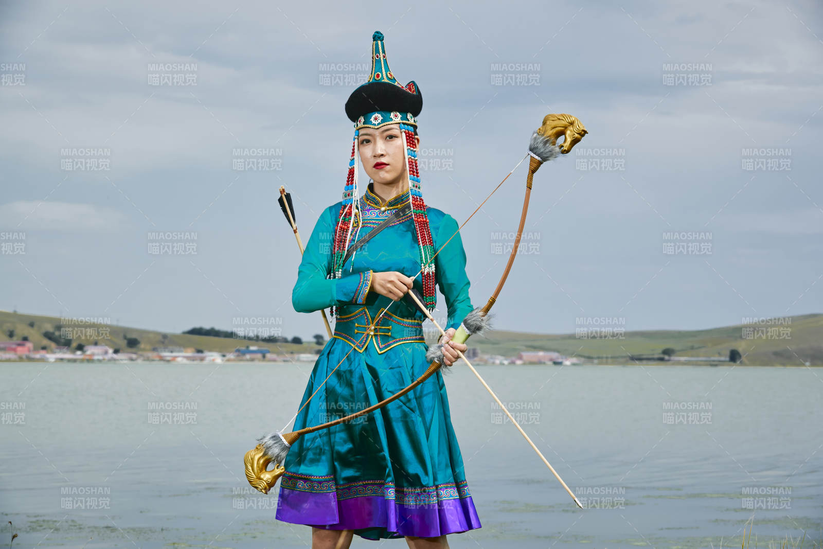草原湖畔身穿蒙古族飾手持弓箭的蒙族少女