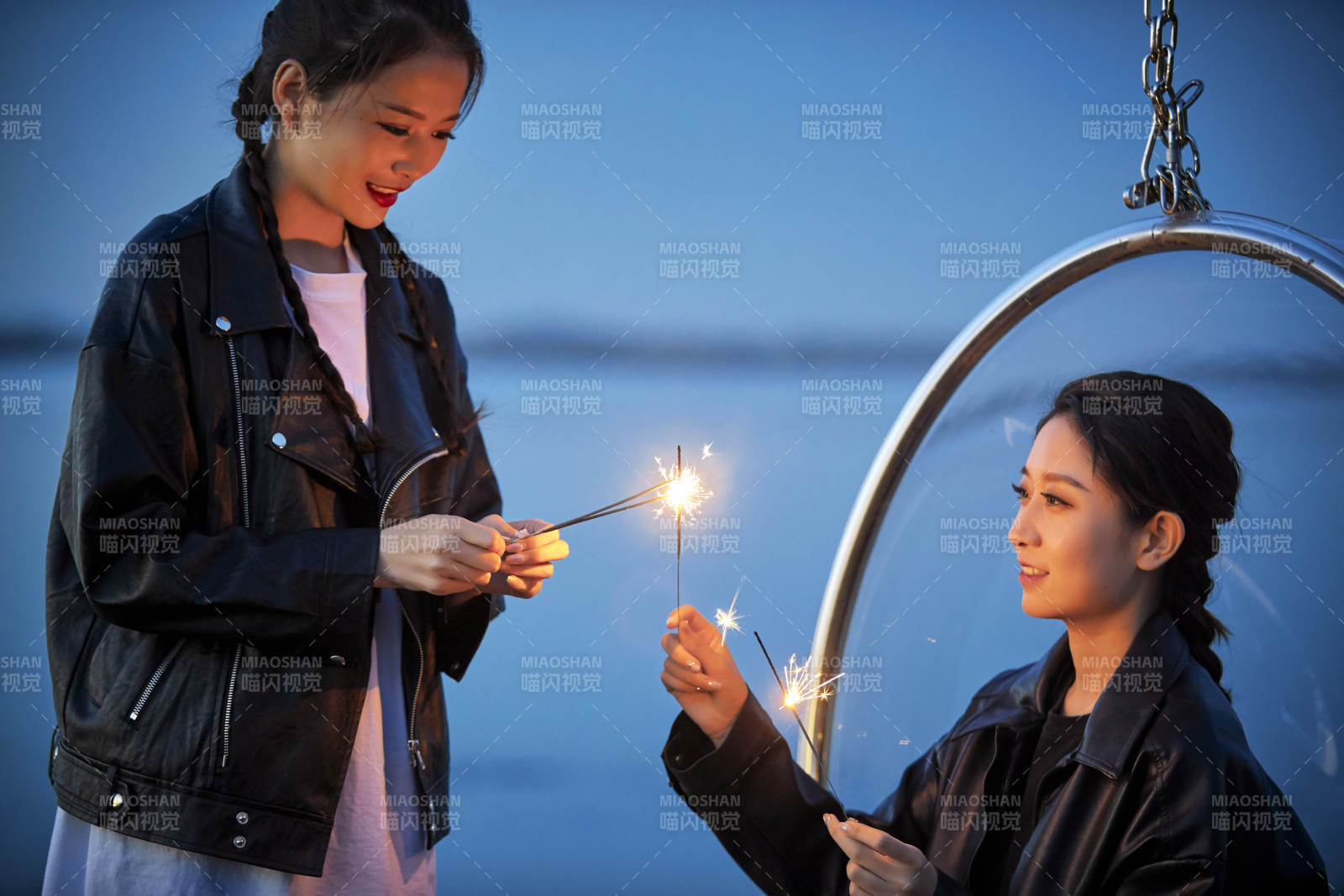 傍晚湖畔透明秋千上燃放仙女棒的可愛少女